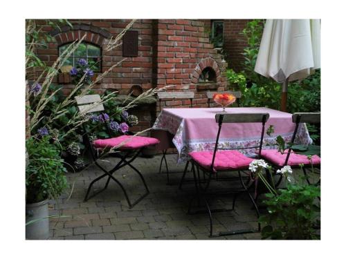 a table with pink cushioned chairs and an umbrella at Dollhouse Modern retreat in Wiesmoor