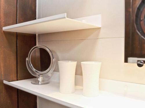 a shelf with two stacks of paper cups and a mirror at Drebach Modern retreat in Drebach