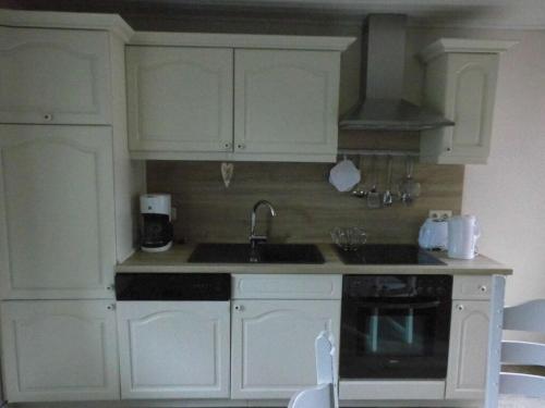 a kitchen with white cabinets and a sink and a stove at Dollhouse Modern retreat in Wiesmoor