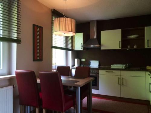 cocina con mesa de madera y sillas rojas en Saaleland Apartment 3 en Schleiz