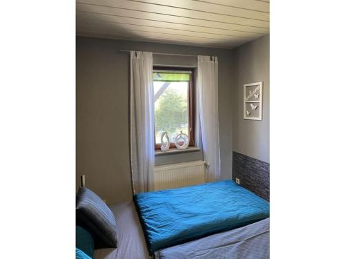a bedroom with a blue bed and a window at am Wald 2 Modern retreat in Kölpinsee