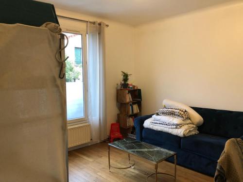 un salon avec un canapé bleu et une fenêtre dans l'établissement Studio Villejuif centre, à Villejuif