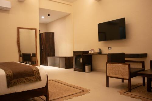 1 dormitorio con 1 cama y TV en la pared en KASHI ANANDAM SPIRITUAL & WELLNESS VEDIC VILLAGE LLP en Kakarmatha