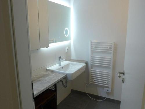 uma casa de banho branca com um lavatório e um espelho em City center Modern retreat em Rostock