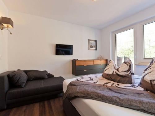 a bedroom with a bed and a couch and a window at Charly"s Sweet Modern retreat in Norderney