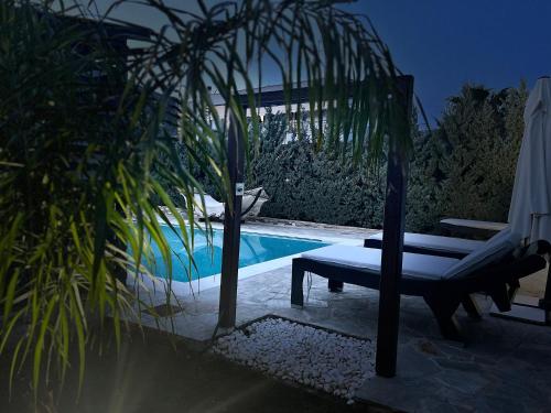 a pool with a bench and palm trees next to it at One Bedroom Pool House by Olivujoj in Anavissos