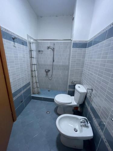 uma casa de banho com um WC, um chuveiro e um lavatório. em Quality Apartaments em Durrës