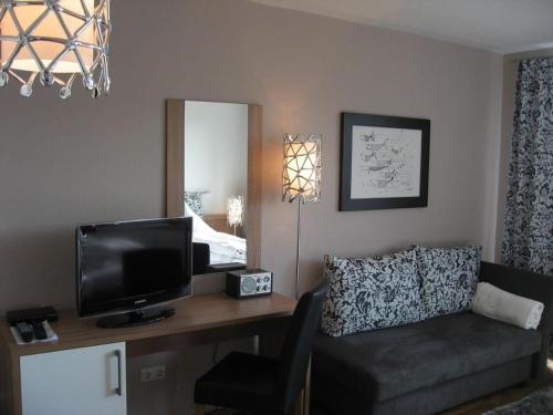 salon z biurkiem, telewizorem i kanapą w obiekcie Saaleland Apartment 1 w mieście Schleiz