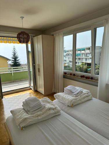 Minusio Swiss Vacances في Minusio: سريرين في غرفة نوم مع نافذة كبيرة