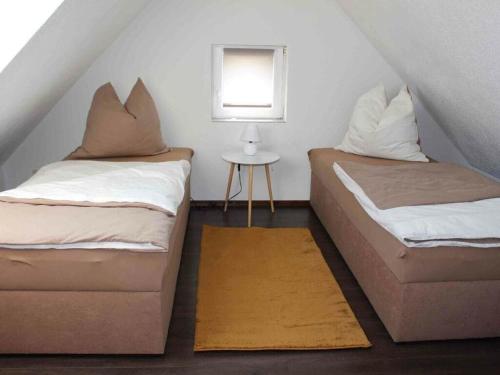 two beds in a small room with a table at Farsighted modern retreat in Annaberg-Buchholz