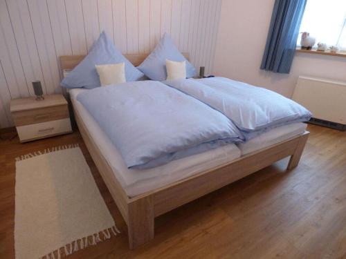 Una cama con sábanas azules y almohadas en un dormitorio en Am Rosengarten Modern retreat, en Sontra