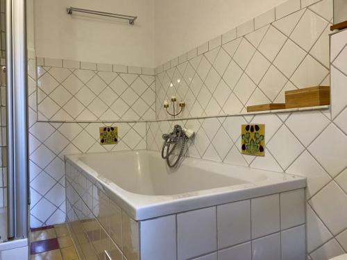 y baño de azulejos blancos con bañera blanca. en Cozy Cottage Modern Retreat en Zankenhausen
