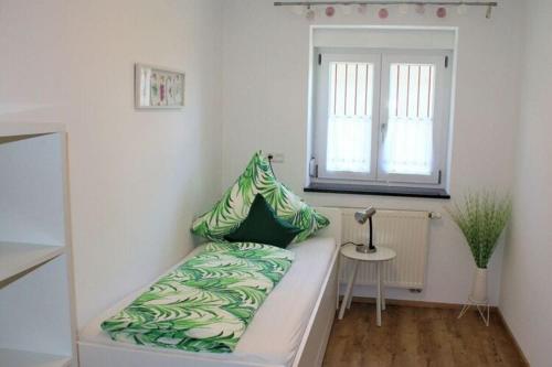 - une chambre avec un lit doté d'oreillers verts et d'une fenêtre dans l'établissement Apartment in Hergensweiler, à Hergensweiler