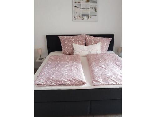 een bed met een roze dekbed en kussens erop bij Lovely apartment in Hesse in Hitzerode