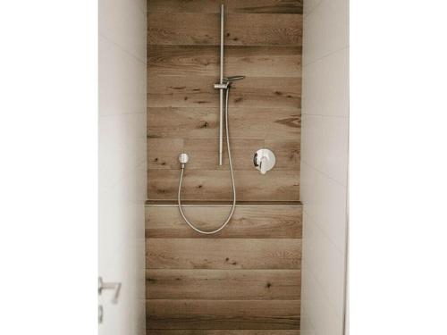 a shower in a bathroom with a wooden wall at Ziegler Modern retreat in Ebersburg