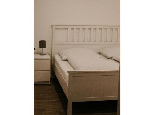 ein Schlafzimmer mit einem weißen Bett und einem Nachttisch in der Unterkunft Ziegler Modern retreat in Ebersburg