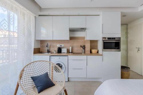 - une cuisine avec des placards blancs et un oreiller bleu sur une chaise dans l'établissement B045-Studio croisette AC close Congress center SEA, à Cannes