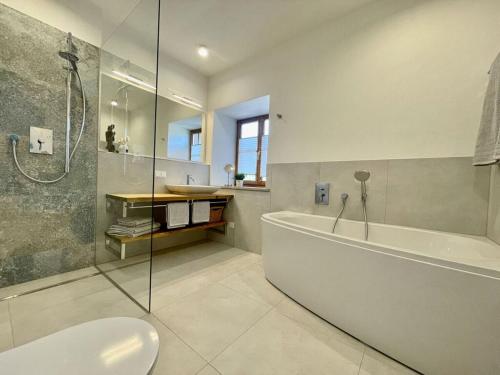 een badkamer met een bad, een douche en een wastafel bij Oberland Stadlberg in Miesbach