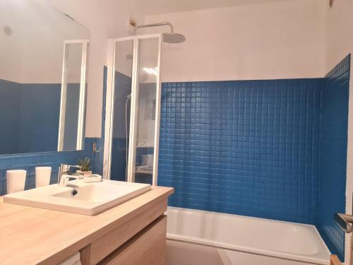 a bathroom with a sink and a tub and blue tiles at Meijotel - 59 - Appt tres spacieux 6-7 pers in Les Deux Alpes