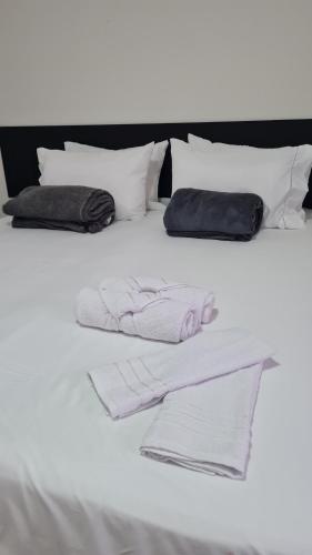 Una cama blanca con toallas y almohadas blancas. en Residencial do Centro en Niterói