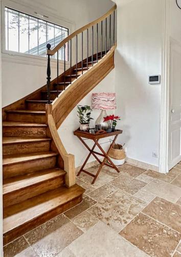 a wooden staircase in a home with a table at La Feuilleraie - Maison de charme avec piscine in Compiègne