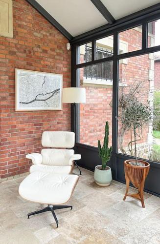 a living room with a white chair and a brick wall at La Feuilleraie - Maison de charme avec piscine in Compiègne