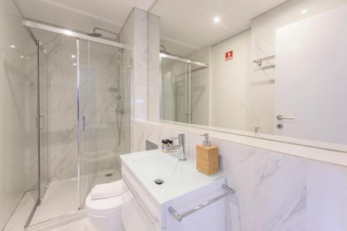 ein weißes Bad mit einem Waschbecken und einer Dusche in der Unterkunft Braga Center Apartments - Rua do Anjo in Braga