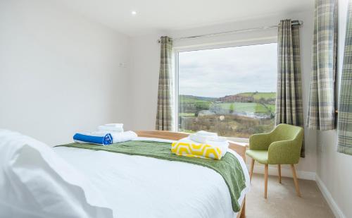a bedroom with a bed and a window and a chair at Llwynblyfyn in Llandeilo