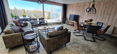 a living room filled with furniture and a large window at Vakantiehuis De Bunker in Julianadorp