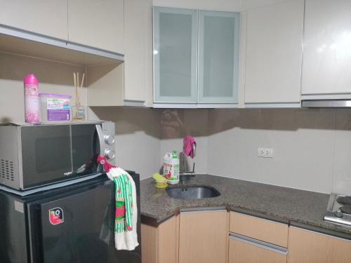 a kitchen with a sink and a microwave at Pasay City Condotel Near Airport in Manila