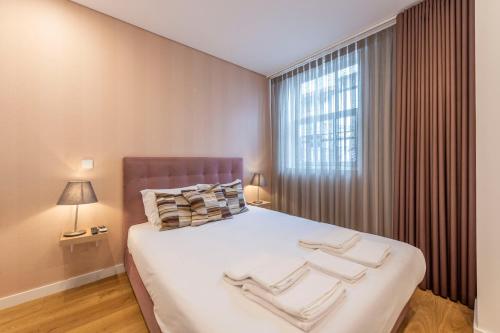 ein Schlafzimmer mit einem großen Bett mit zwei Handtüchern darauf in der Unterkunft Braga Center Apartments - Rua do Anjo in Braga