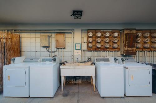 a laundry room with three washing machines and a sink at Waikiki Heritage Hotel in Honolulu