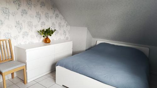 ein Schlafzimmer mit einem Bett mit einer Kommode und einem Stuhl in der Unterkunft Appartement les argousiers in Oye-Plage