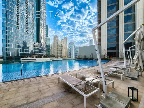 a swimming pool with chaise lounges in a city at 52 I 42 Tower by Emaar, Dubai Marina in Dubai