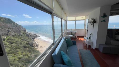 a room with a couch and a view of the beach at Blue LightHouse Sesimbra in Sesimbra