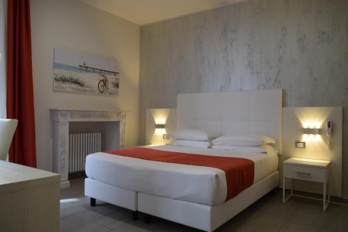 a bedroom with a large white bed and a fireplace at Hotel Lido in Varazze