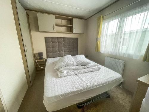 a bed with white sheets and pillows in a room at Lovely Caravan With Decking At Manor Park In Hunstanton Ref 23091t in Hunstanton