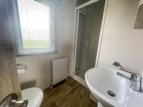 a white bathroom with a sink and a shower at Lovely Caravan With Decking At Manor Park In Hunstanton Ref 23091t in Hunstanton