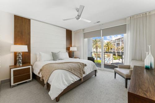 a bedroom with a bed and a chair and a window at the Pointe Unit 125 in Rosemary Beach