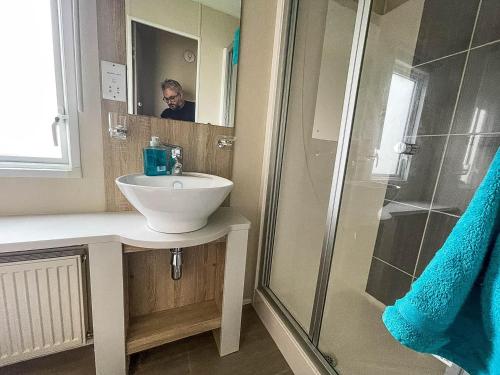 een badkamer met een wastafel en een douche met een persoon in de spiegel bij 6 Berth Caravan With Wifi At Wells-next-the-sea In Norfolk Ref 72032t in Wells next the Sea
