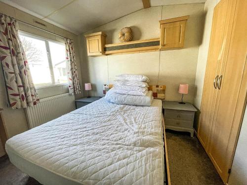 a bedroom with a bed with white sheets and a window at Superb 6 Berth Caravan At Sunnydale Holiday Park Ref 35079a in Louth