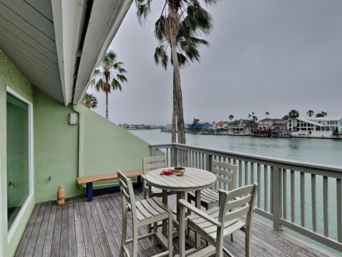 a table and chairs on a porch with the water at Sunset Water View in Padre Island