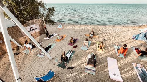 um grupo de pessoas sentadas na areia na praia em Przyczepy Kempingowe CHAŁUPY 6, KITE CREW Surf School em Chałupy