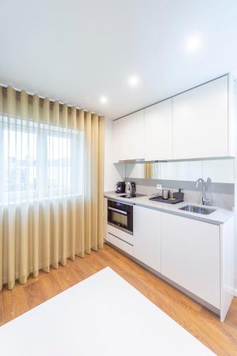 a kitchen with white cabinets and a sink at Terro Collection - Eça de Queirós in Braga