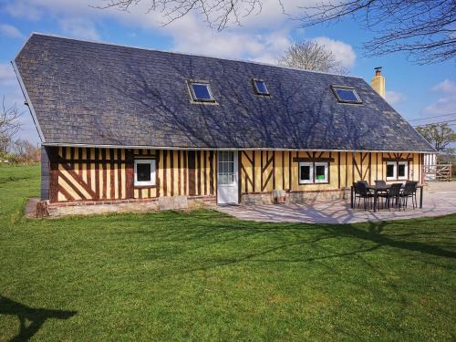 a large wooden house with a table and chairs at La Bergerie in Cambremer