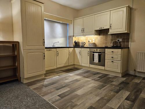 a kitchen with white cabinets and a wooden floor at Main Street Swinford! in Swinford