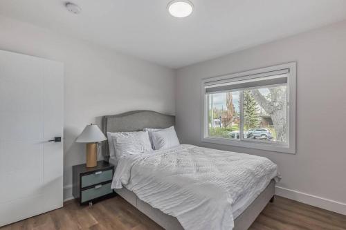 a white bedroom with a bed and a window at Dream Glam in Calgary