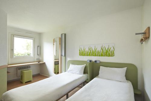 um quarto com duas camas e uma janela em ibis budget Blois Centre em Blois