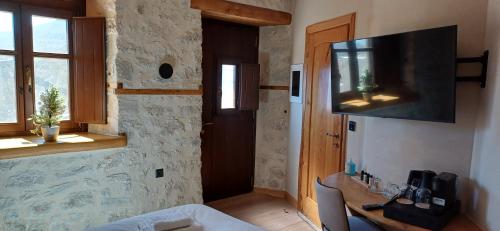 um quarto com uma mesa e uma televisão na parede em Casagli Luxury Suites em Dimitsana