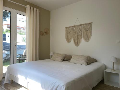 un letto bianco in una camera da letto con finestra di LA VILLA ALBA a Les Issambres
